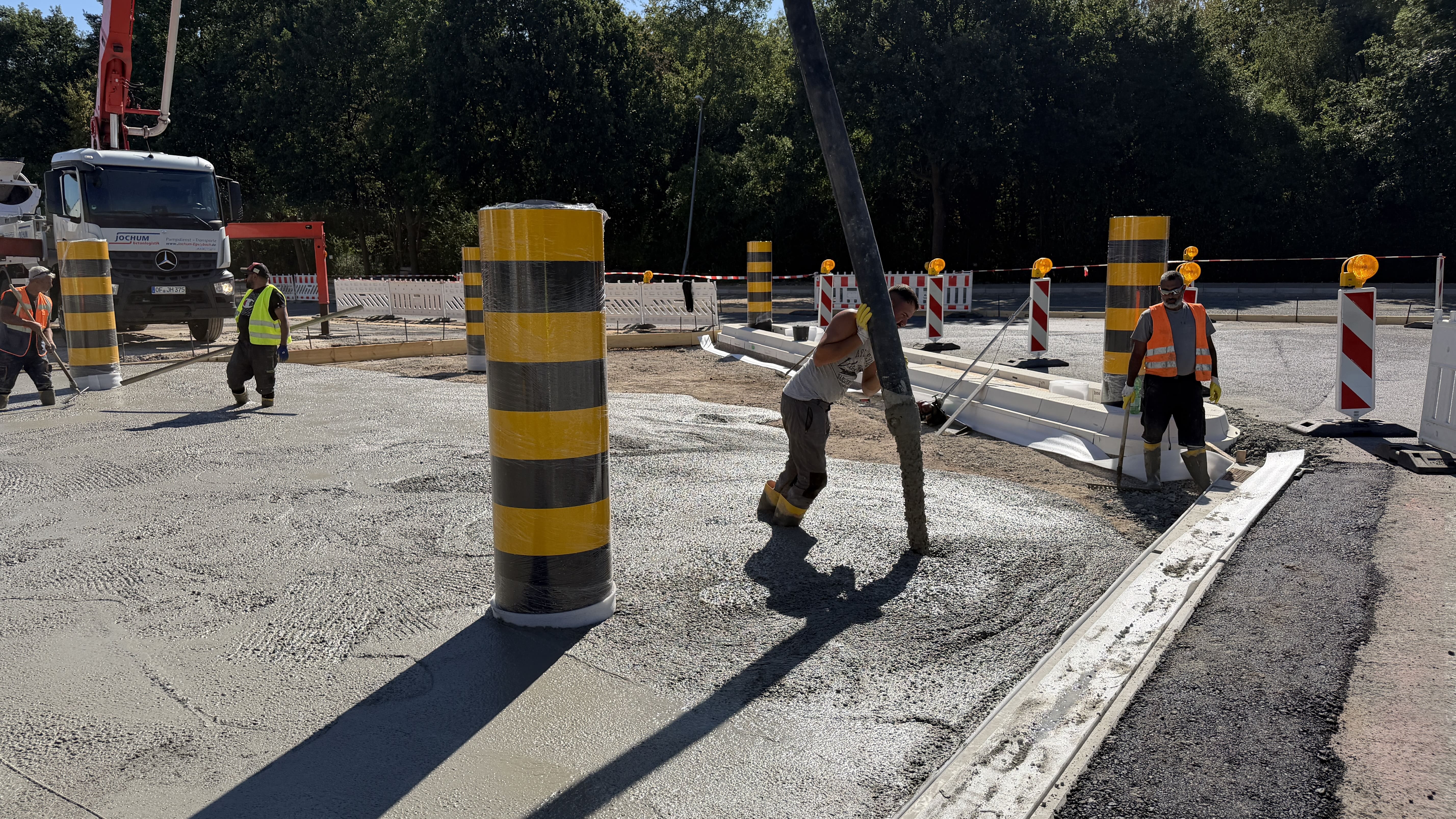 Arbeiter verteilen den flüssigen Beton aus dem Pumpenschlauch auf der Bodenplatte.